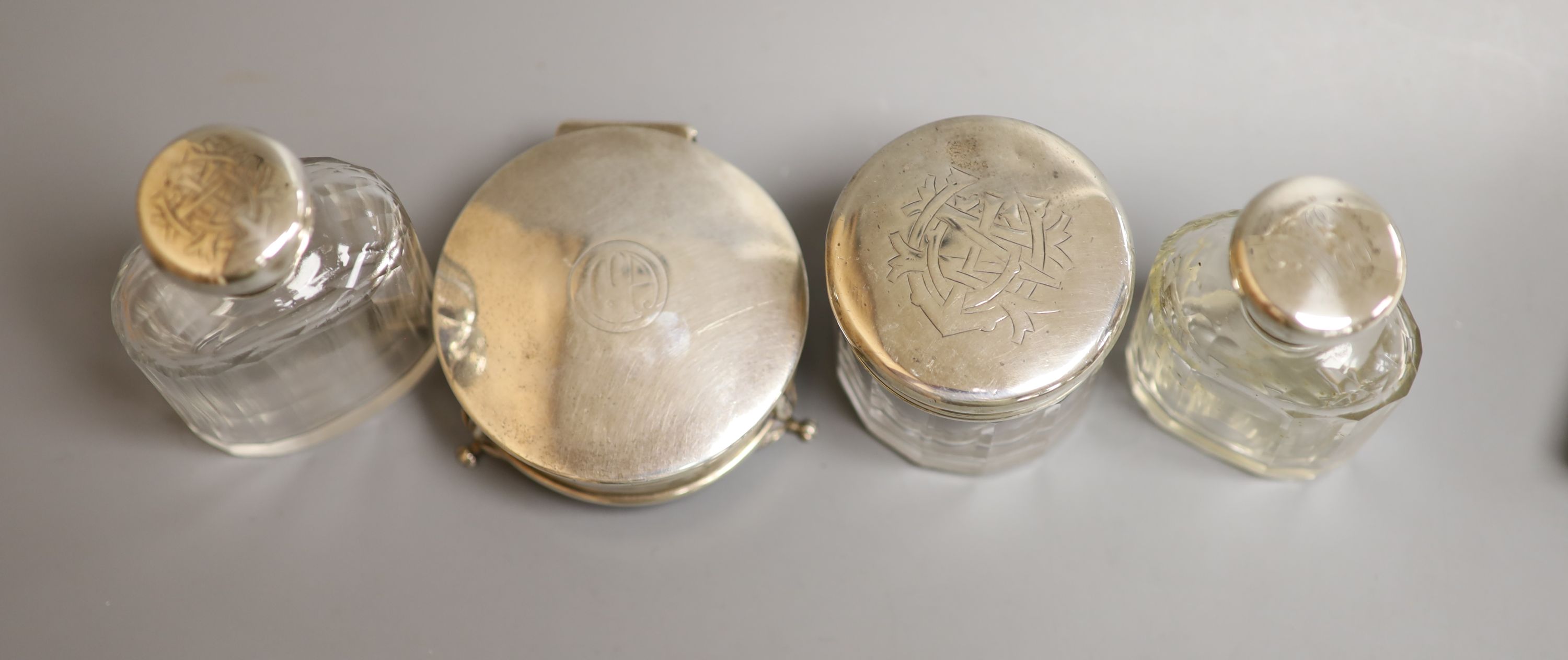 Three silver mounted glass toilet bottles and a George V silver mounted circular trinket box by Mappin & Webb, 77mm.